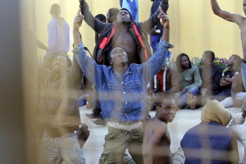 Inmigrantes subsaharianos cantan con las manos al aire, otros estn...