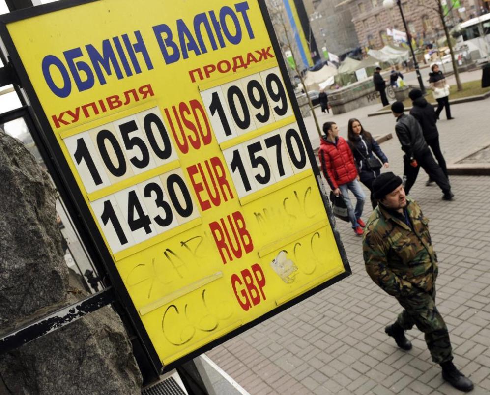 Varias personas pasan por una oficina de cambio en Kiev, hoy. Con un...