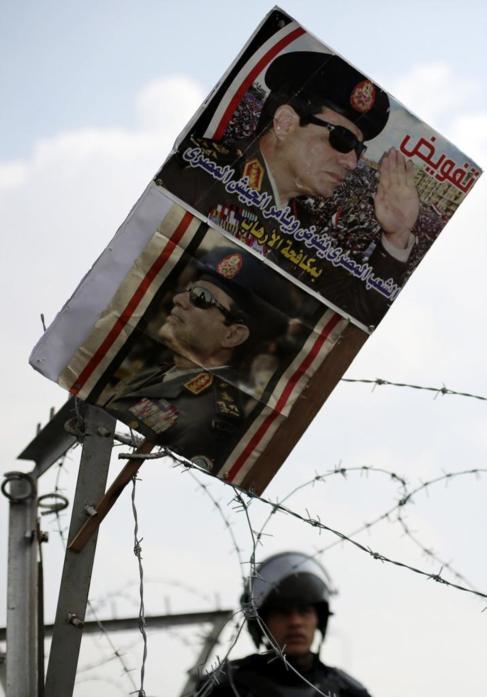 Un poster de Al Sisi frente a un polica.