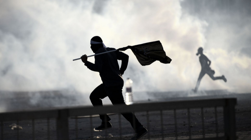 Manifestantes bahreines corren a esconderse del gas lacrimgeno...