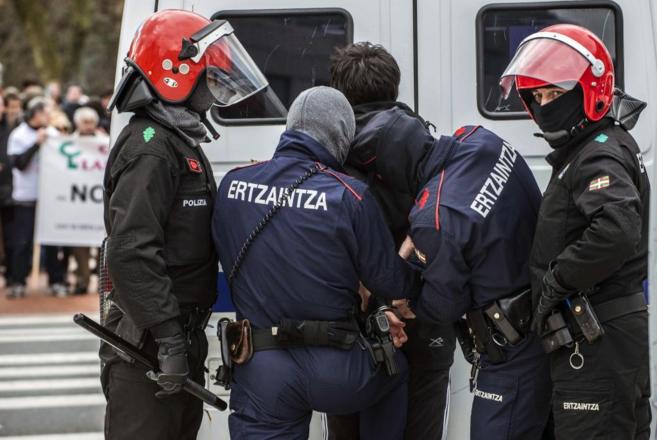 Agentes de la Ertzaintza con uno de los detenidos el lunes.