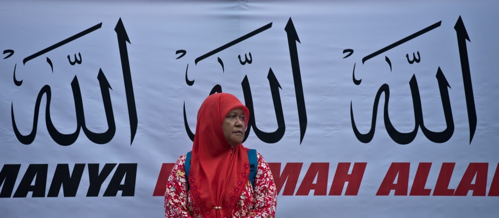 Una musulmana de Malasia se encuentra delante de una pancarta que...