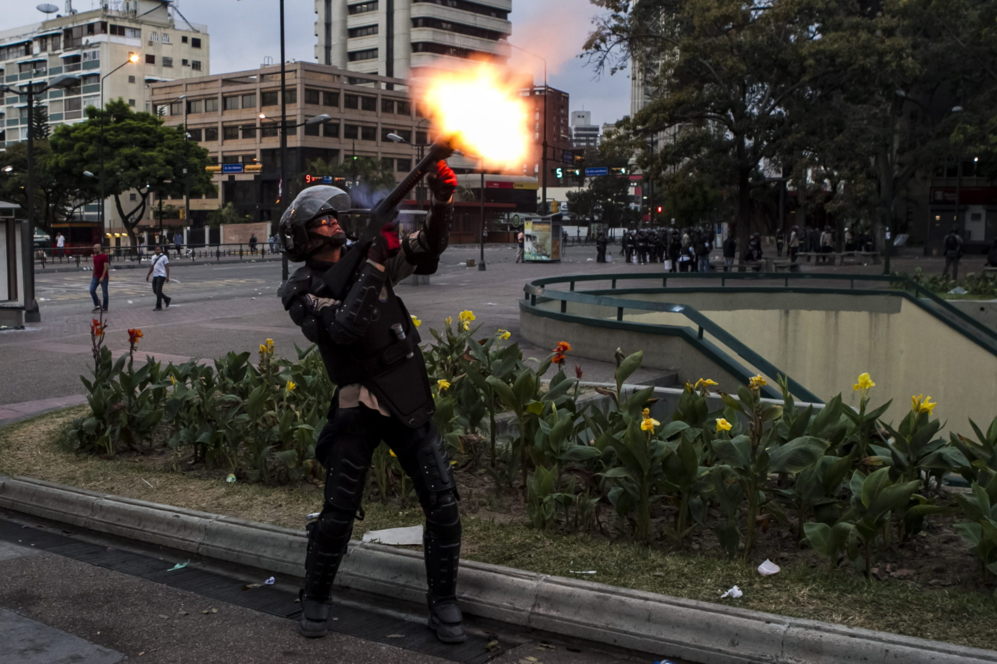 Un agente de la Polica Bolivariana Lanza una granada de gas contra...