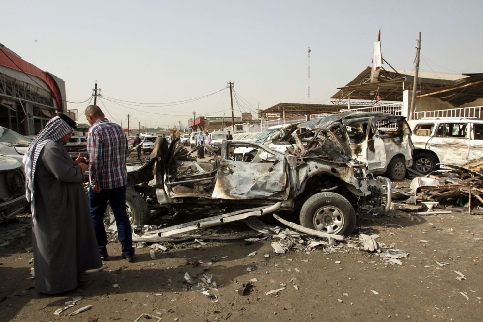 Iraques se sitan cerca de vehculos quemados despus de un...