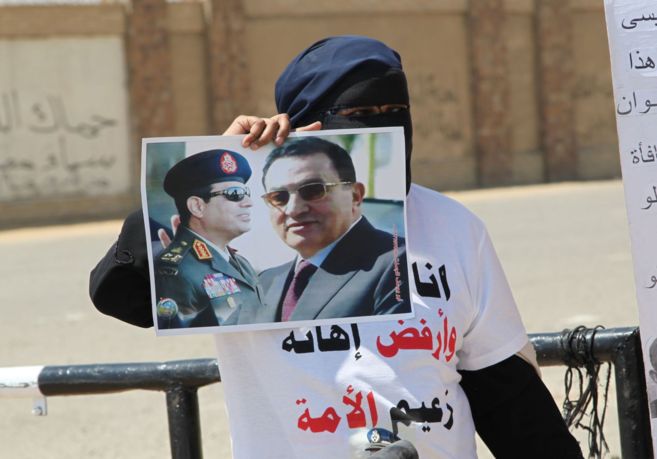 Una mujer ensea un cartel de Mubarak y del general Al Sisi a las...