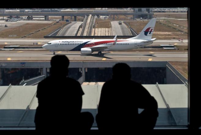 Pasajeros contemplan un avin de Malaysia Airlines en el aeropuerto...
