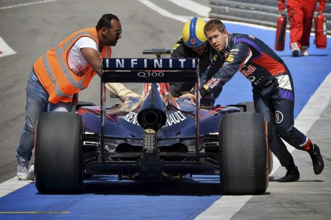 Vettel empuja su coche averiado junto con un mecánico y un comisario...
