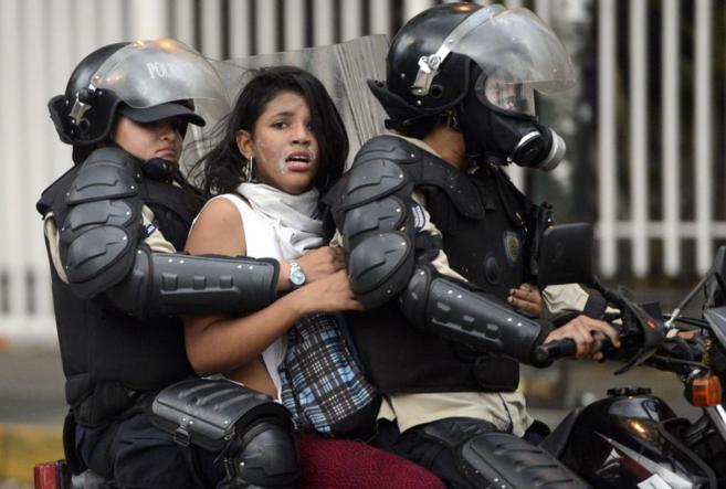 Una activista antigubernamental, detenida por dos agentes venezolanos...