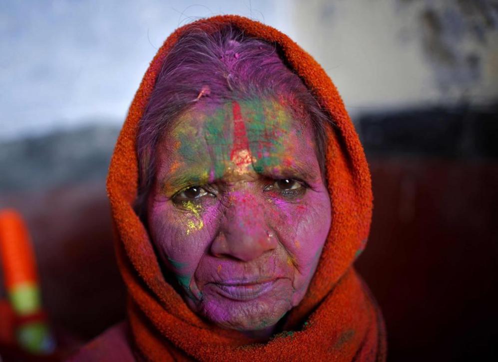 Una mujer viuda, con la cara cubierta de distintos colores, contempla...