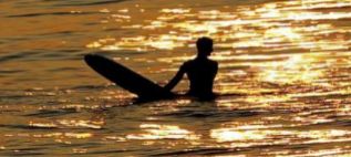 Un surfista en el agua, con su tabla en el mar. El agua est naranjo...