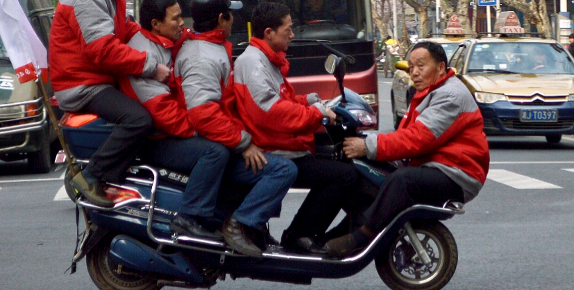 Cinco hombres se sientan en una bicicleta elctrica para cruzar una...
