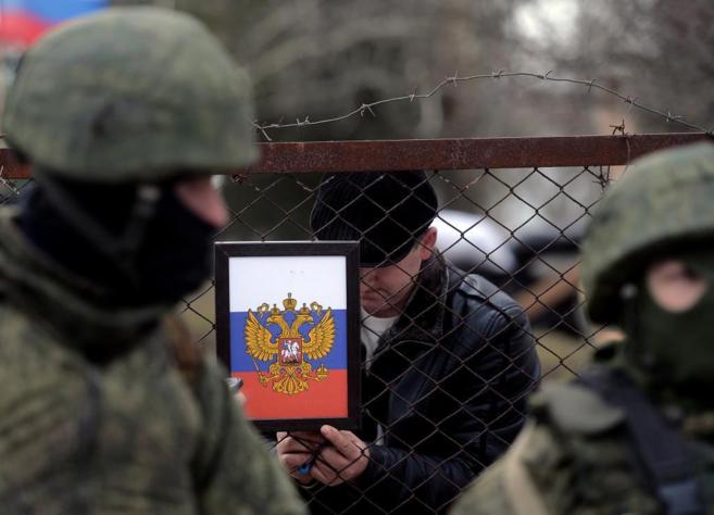 Un hombre cola el escudo de armas ruso en la verja de una de las bases...