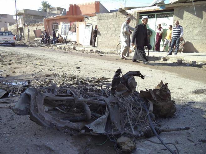Varios iraques cerca de los restos del coche bomba que deton en...
