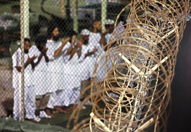 Un grupo de presos reza cerca de una alambrada en Guantnamo, la base...