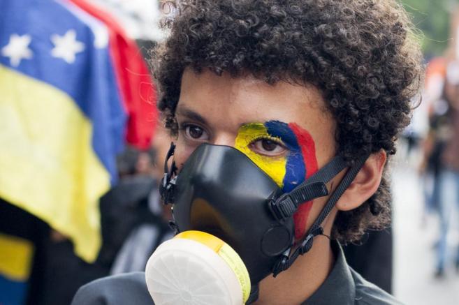 Un manifestante opositor al Gobierno venezolano marcha por las calles...