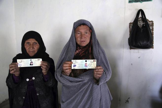 Dos mujeres afganas muestran su tarjeta de registro para votar para...