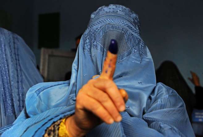 Una afgana muestra el dedo manchado de tinta despus de votar en un...