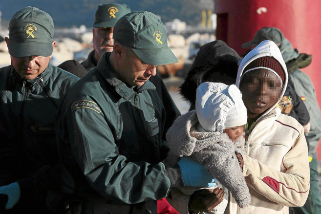 Un guardia ayuda a una mujer subsahariana y su hijo, llegados en...