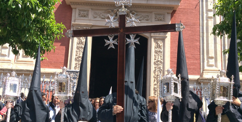 La cruz de gua de la Borriquita, portada por nazarenos del Amor.