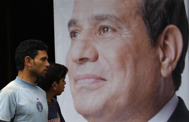 Dos egipcios pasan frente a un cartel electoral de Abdelfatah al Sisi...