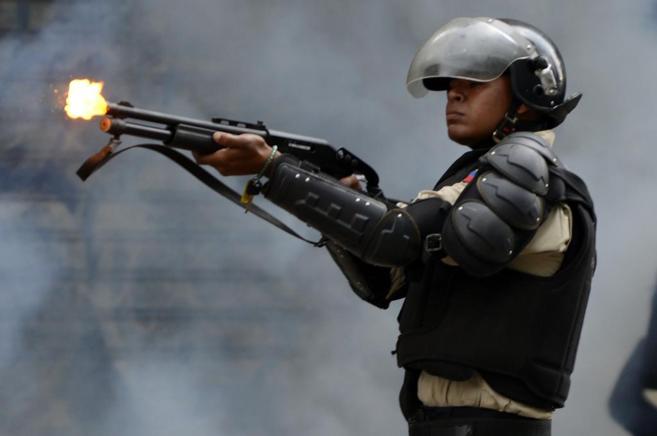 Un policía venezolano dispara su arma frente a los estudiantes en...