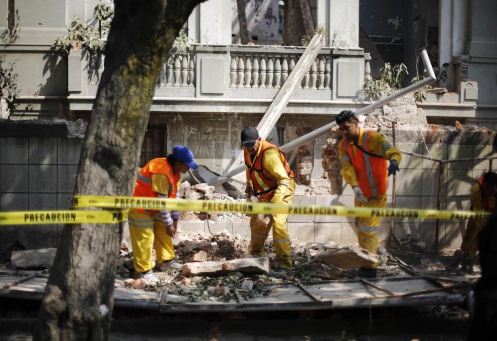 Trabajadores municipales retiran los escombros de un muro derrumbado...