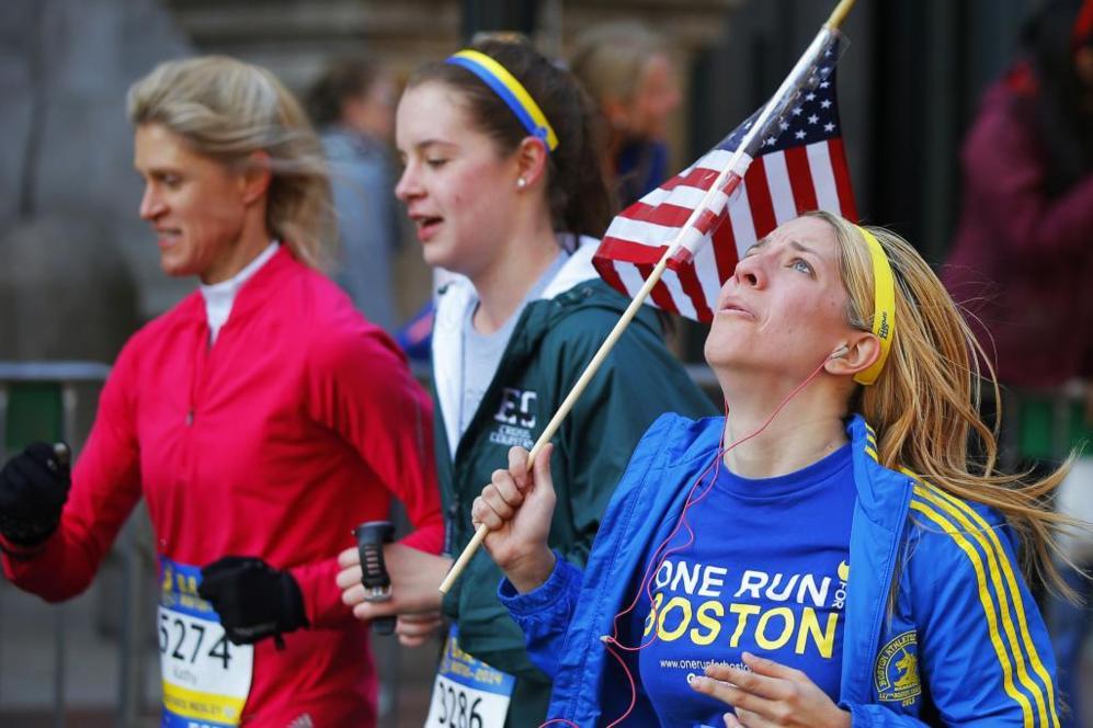Una corredora porta la bandera de EEUU como homenaje a los fallecidos...