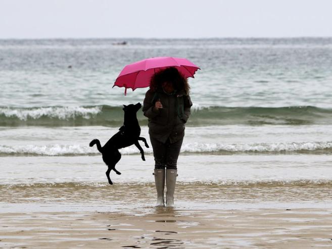 Una mujer pasea a su perro en la playa de la Concha el Domingo de...