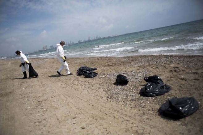 Los operarios de limpieza recogiendo los restos de fuel en la playa de...