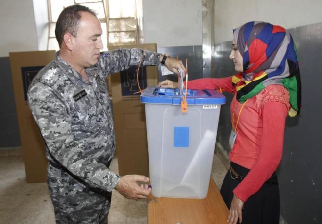 Un polica iraqu introduce su voto en una urna en la ciudad de...