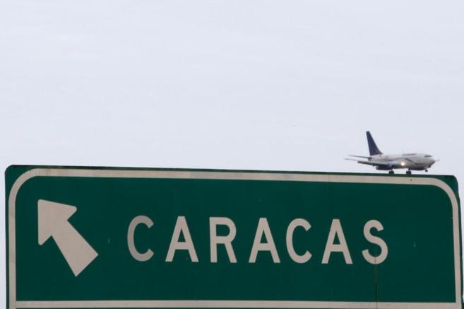 Un avión sobrevuela un cartel indicando la dirección de Caracas en...