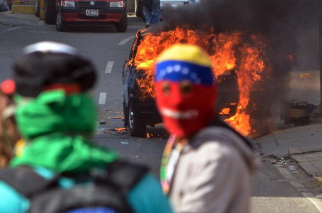 Un enmascarado quema un coche de la Guardia Nacional en una protesta...