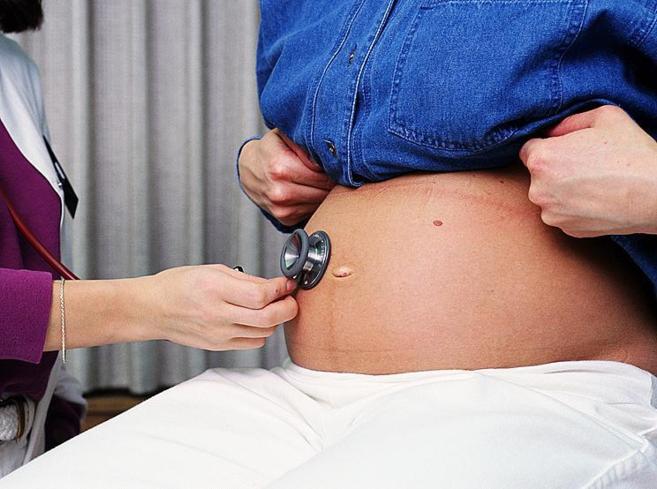 Ginecóloga auscultando a una mujer embarazada.