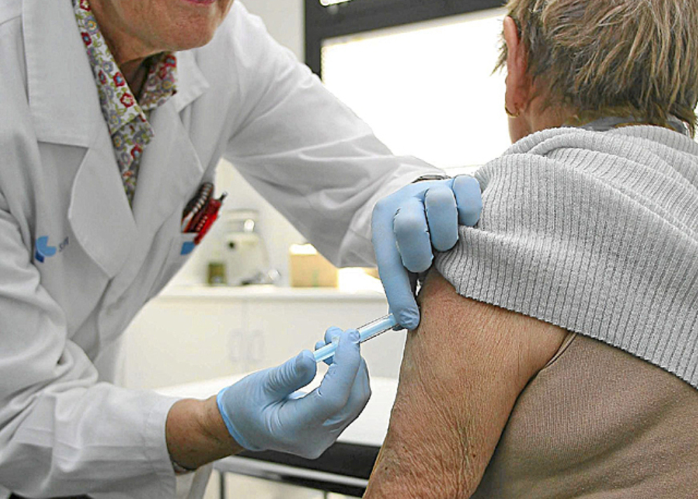 Un sanitario vacuna a una mujer contra la gripe.