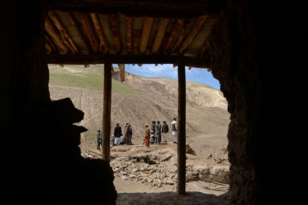 Afganos miran el lugar donde se produjo el deslizamiento de tierra que...
