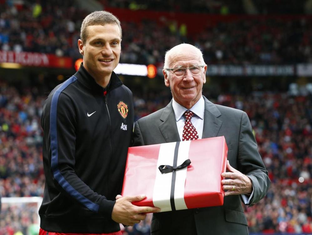 Vidic recibe un regalo conmemorativo de manos de Bobby Charlton.