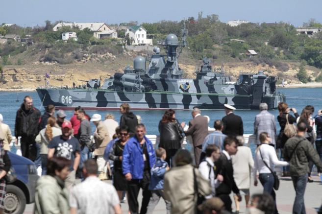 Decenas de ucranianos pasean junto a un buque ruso anclado en el...