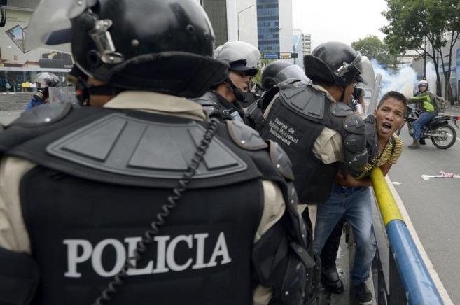 La policía venezolana acorrala a un joven durante las protestas de...