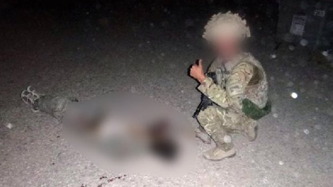 Un miembro de la RAF, junto al cadvver de un talibn, mostrando el...