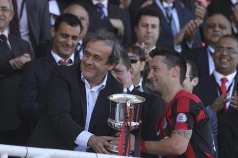 Platini entrega el trofeo tras el partido en el Victoria Stadium.