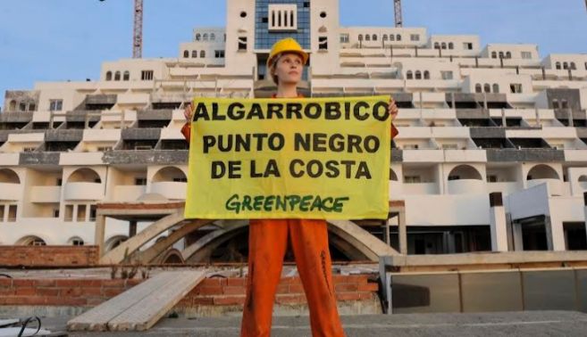 Una activista de Greenpeace posa delante del hotel pintado de negro,...