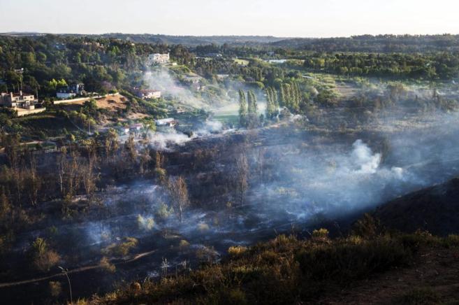 El humo cubre una extensin de tierra quemada en un incendio al norte...