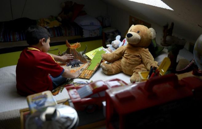 Un niño de espaldas juega en una cama llena de juguetes