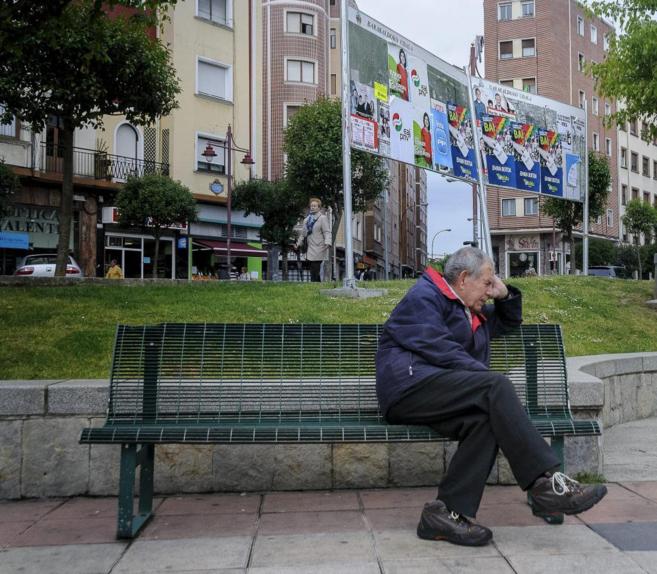 Un vecino de Barakaldo (Vizcaya), en un banco frente a carteles...