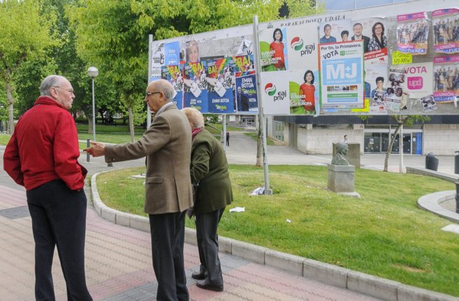 Tres jubilados ante carteles electorales en Barakaldo.