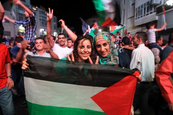 Aficionados palestinos celebran en Ramallah la victoria de su equipo...