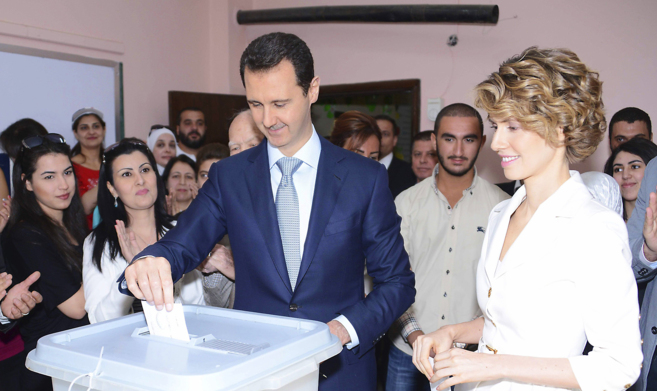 El presidente sirio, Bashar Asad, vota junto a su esposa Asma en un...