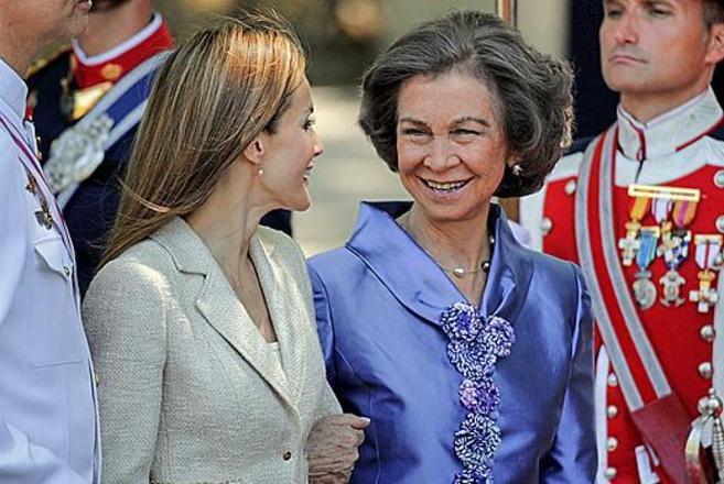 La Reina y Letizia sonren, agarradas del brazo.