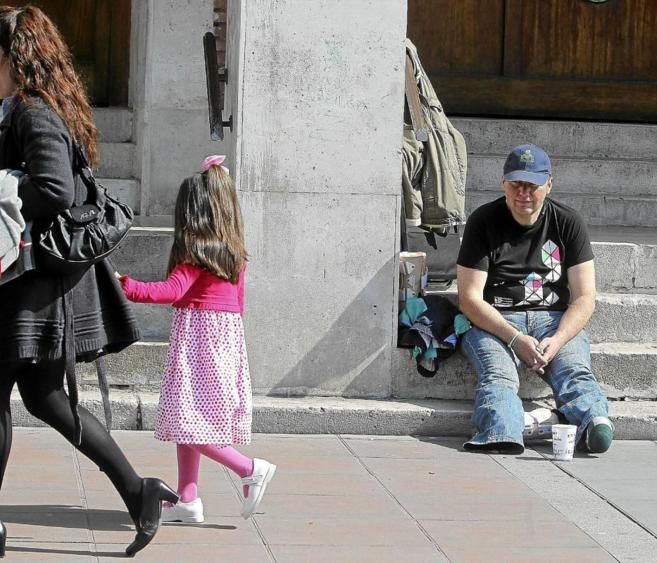 Una pequea observa a un hombre que pide limosna en la calle.