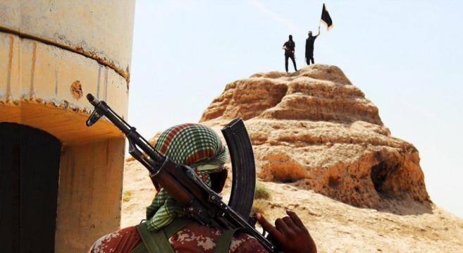 Militantes de ISIS ondean una bandera negra en un puesto de control en...